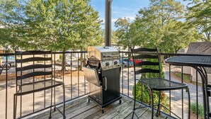 An outdoor patio with a grill, metal chairs, and a table. -  Stylish & Centrally-Located 2 bed/2 bath Condo in Auburn, AL (Auburn)