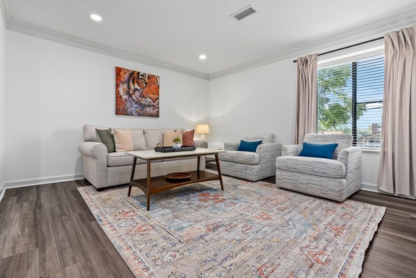 A living room with two sofas, a coffee table, a rug, and a painting on the wall.