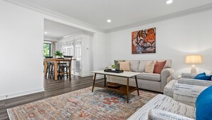 A living room with a sofa, coffee table, and a rug. There is a painting on the wall and a lamp on the side. -  Stylish & Centrally-Located 2 bed/2 bath Condo in Auburn, AL (Auburn)