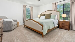 A bedroom with a bed, a nightstand, a chair, a ceiling fan, and a window with curtains. -  Stylish & Centrally-Located 2 bed/2 bath Condo in Auburn, AL (Auburn)