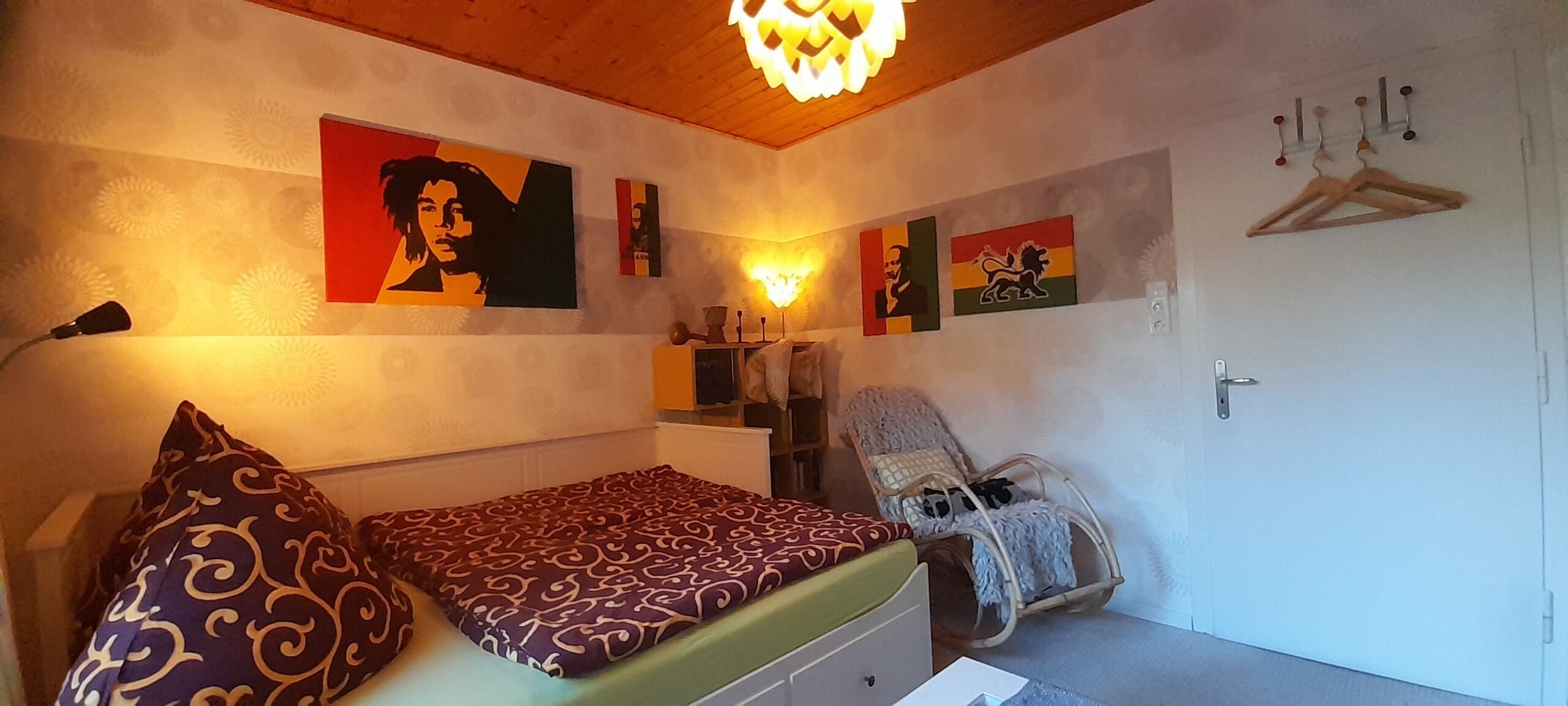 A bedroom with a bed, a chair, and wall art.