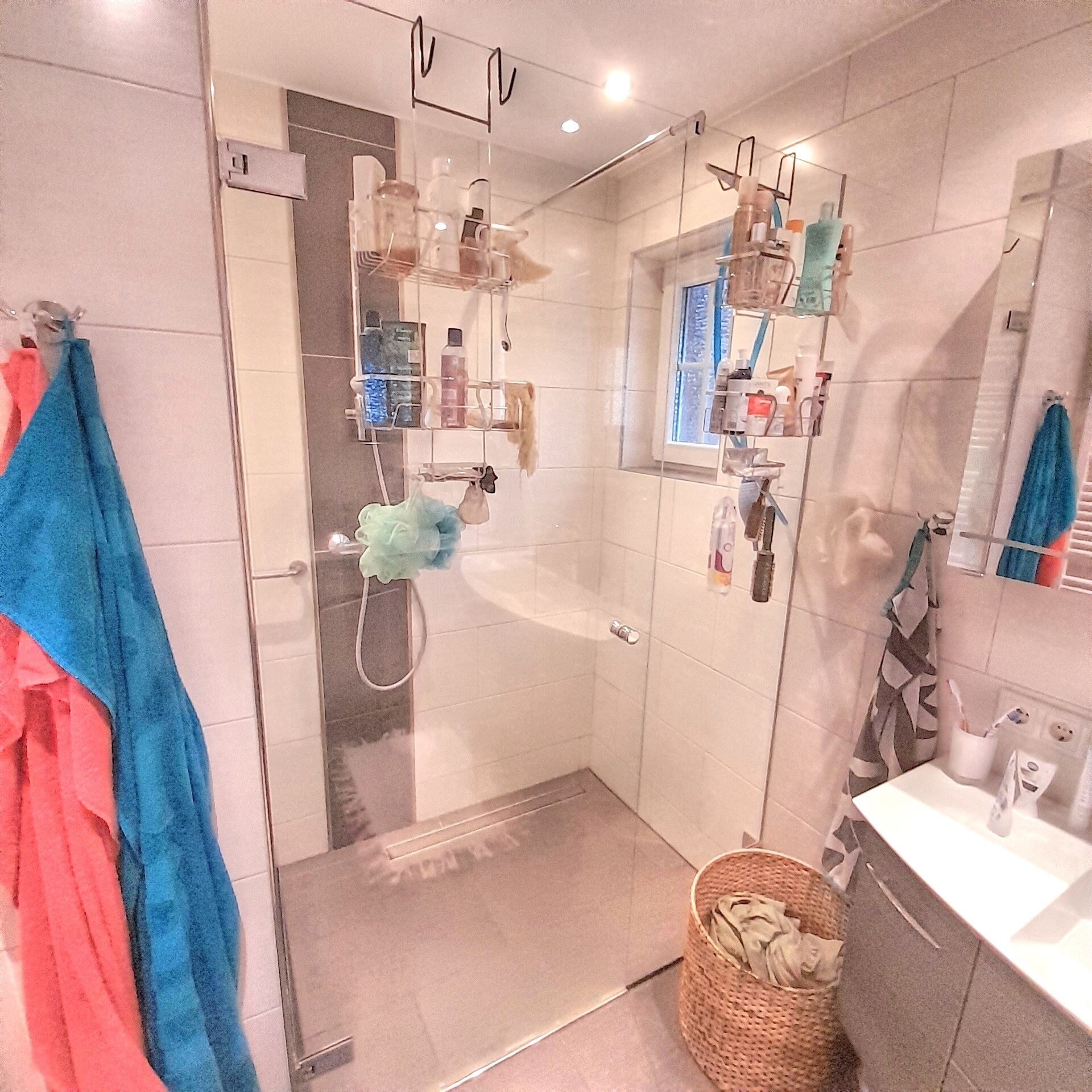 Ein modernes Badezimmer mit Duschkabine aus Glas, einem Waschbecken und einem Spiegel.