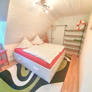A bedroom with a bed, a small table, a ladder, and a life preserver on the wall. - Hakuna Matata - Comfortability in Oldenburg (Hatten)
