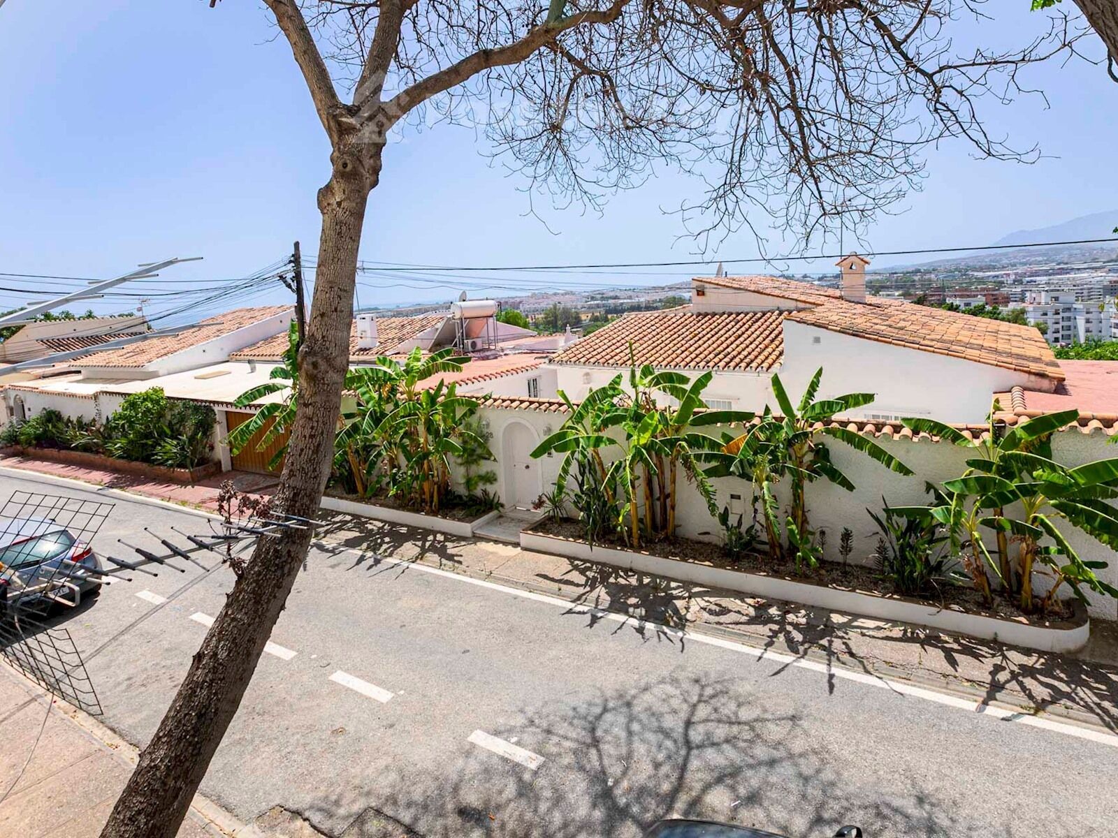 Un quartier résidentiel où les maisons sont dotées de toits en tuiles et où l’on peut voir des bananiers.