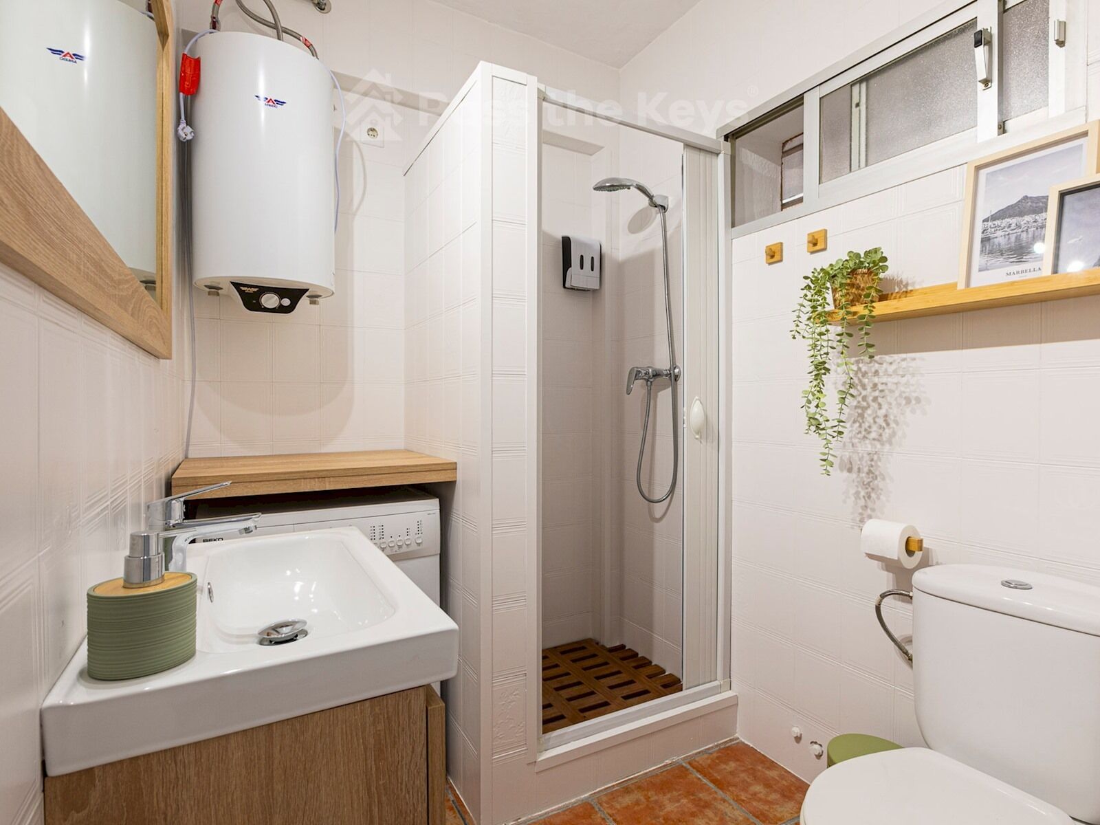 Ein kleines Badezimmer mit Dusche, Toilette, Waschbecken und Warmwasserbereiter.
