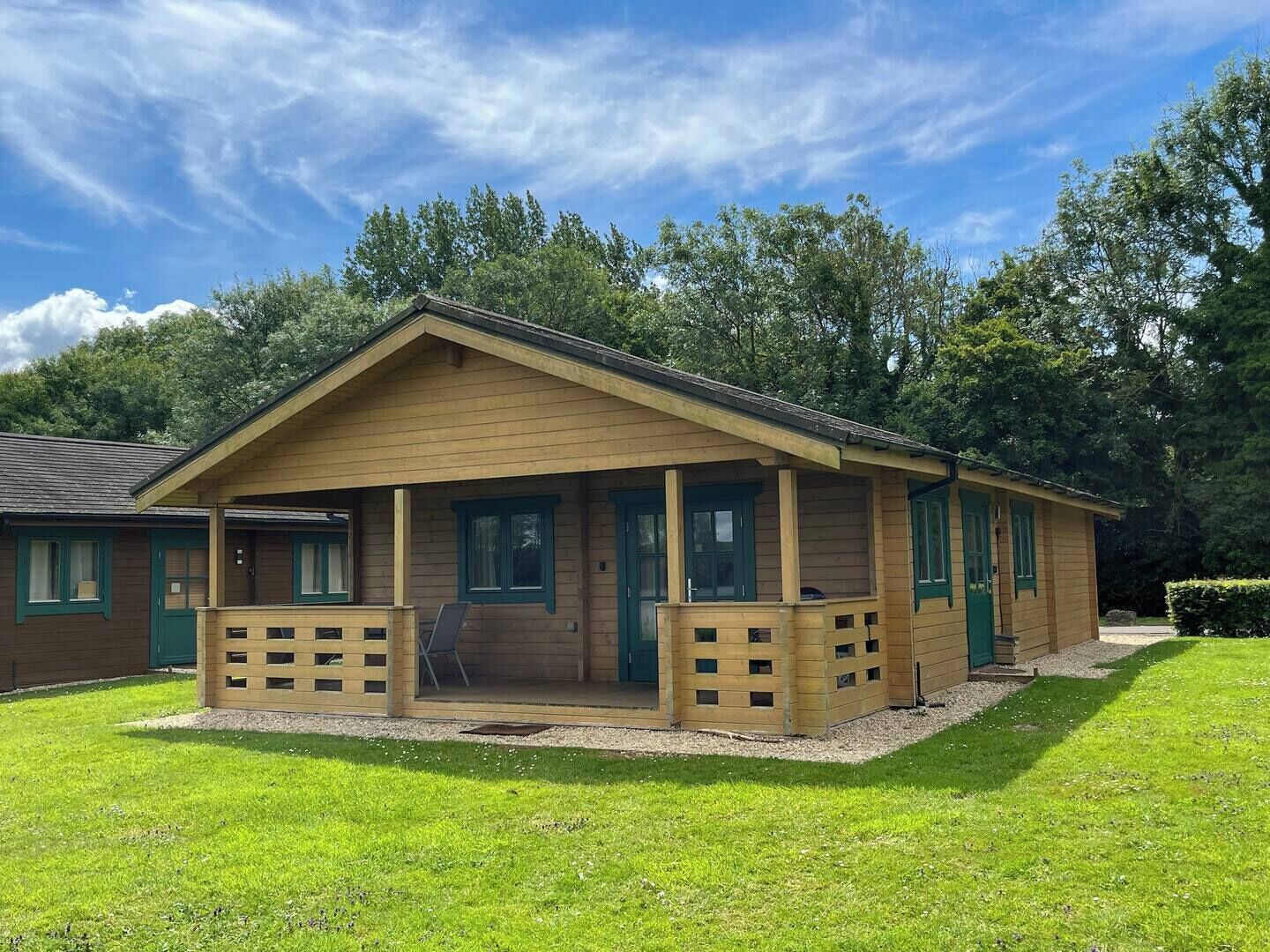 A wooden lodge with a porch, multiple windows, and a grassy lawn.