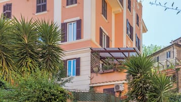 Un edificio a più piani con una scala che conduce all'ingresso, immerso nel verde.
