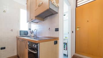 Una cucina compatta con mobili in legno, un forno a microonde e un lavello.