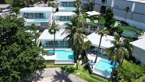 A modern resort with multiple swimming pools, palm trees, and a clear blue sky. - Replay Pool Villa  (Koh Samui)