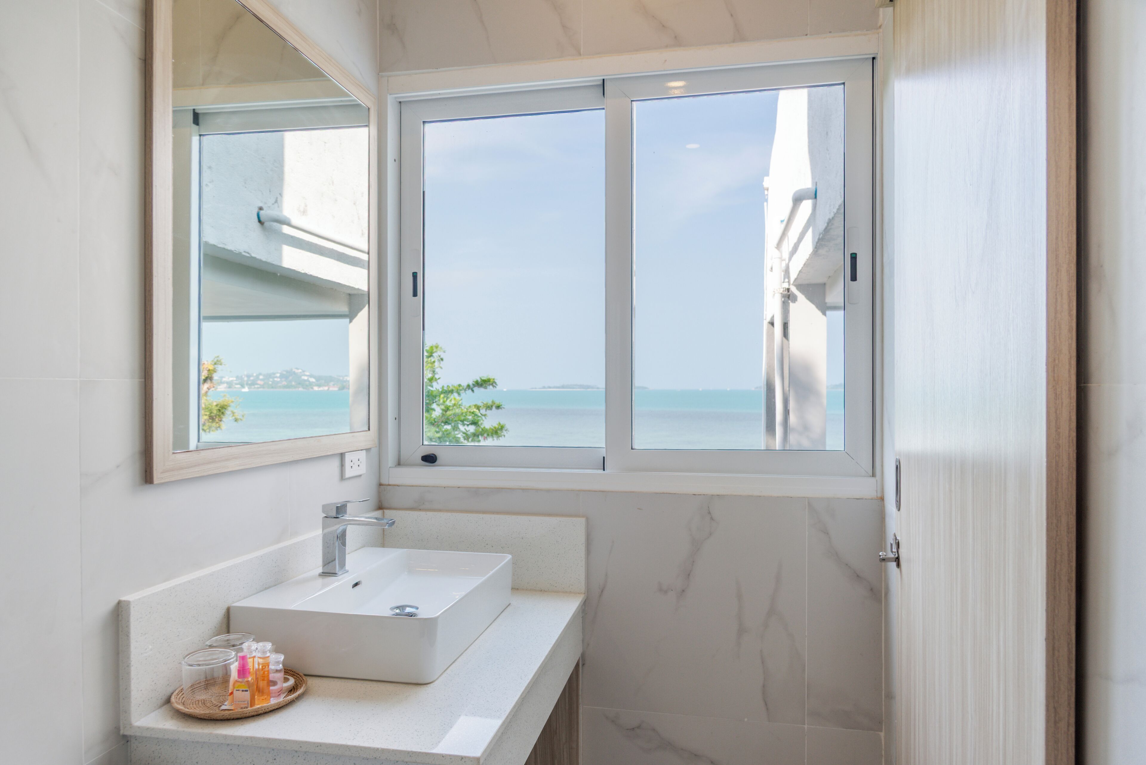 A bathroom with a large window, a sink, and a mirror.
