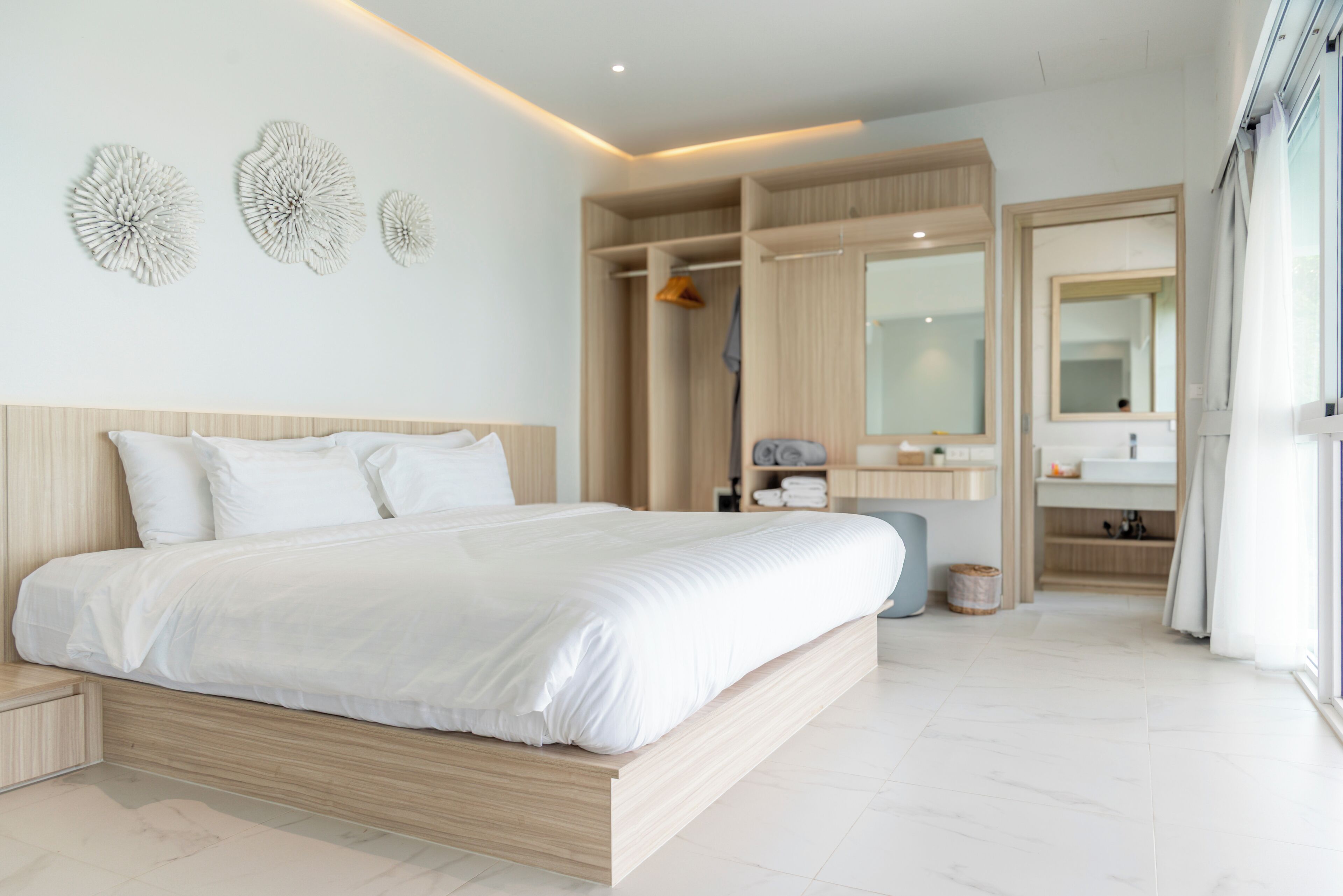 Une chambre moderne avec un grand lit, une armoire intégrée et une salle de bain équipée d’un miroir et d’un lavabo.
