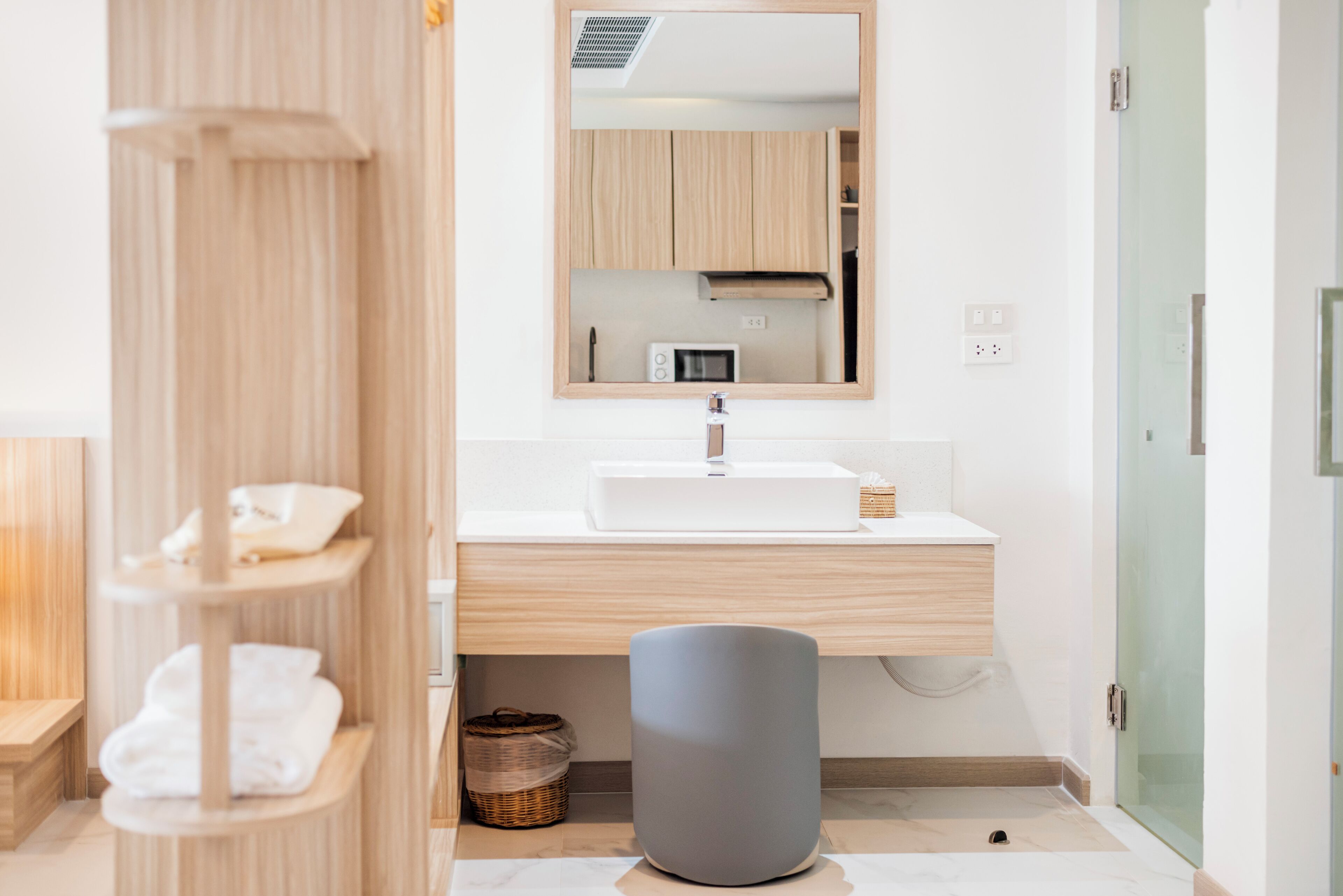Une salle de bain moderne avec un lavabo blanc, un meuble-lavabo en bois et un miroir au-dessus.