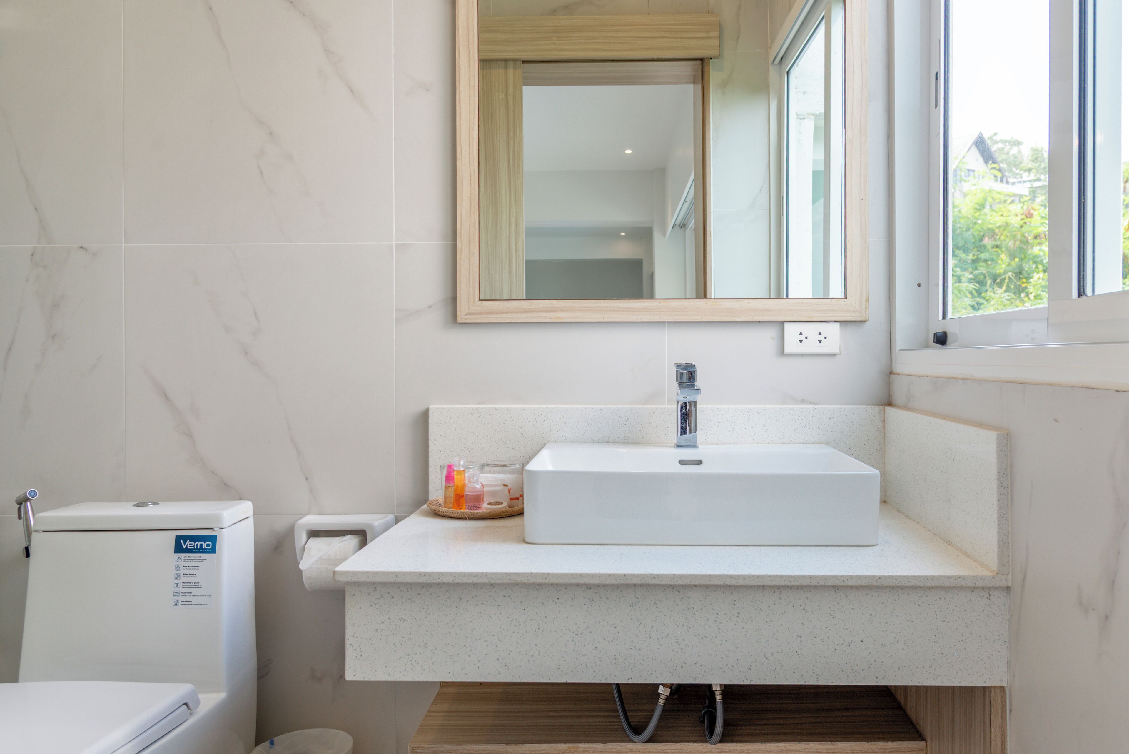 Un bany modern amb un lavabo blanc, un mirall i un vàter.