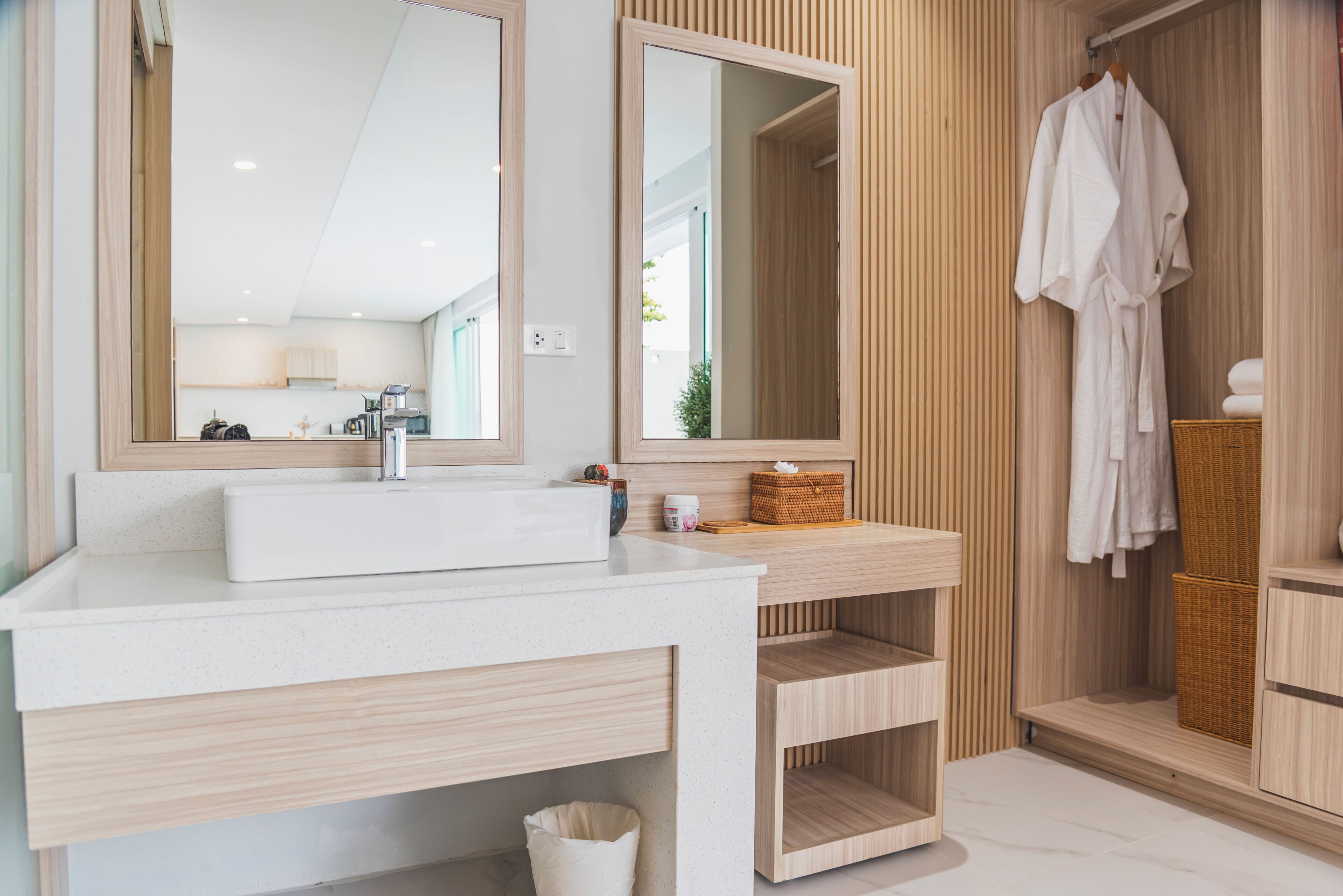 A modern bathroom with a white sink, two mirrors, and wooden paneling.