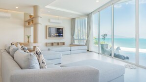 A modern living room with a large window, a ceiling fan, and a flat-screen TV mounted on the wall. - Replay Pool Villa  (Koh Samui)