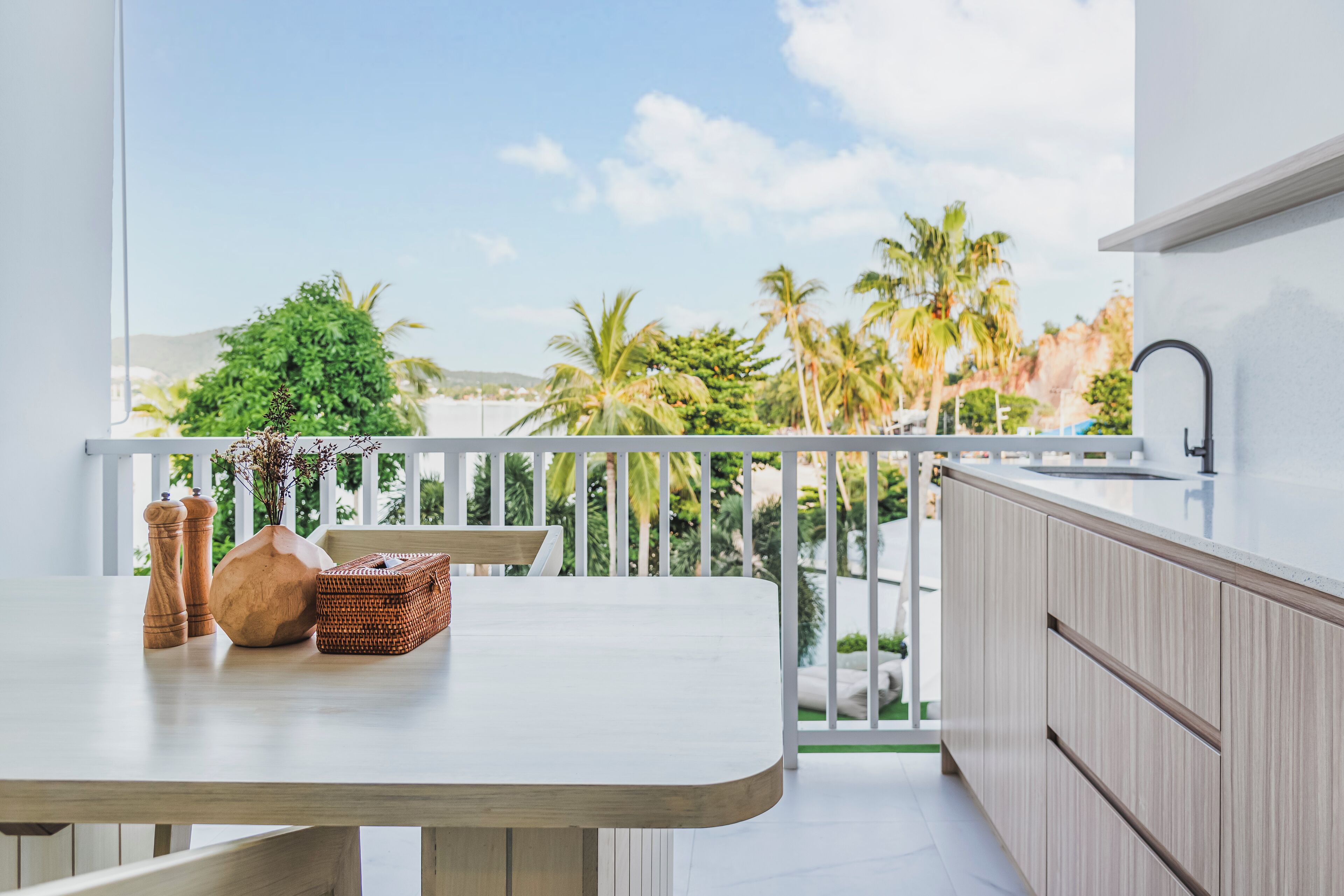 A balcony with a view of palm trees and a white railing.