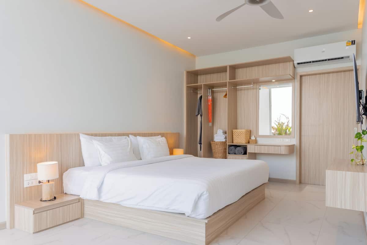 A modern hotel room with a large bed, built-in wardrobe, and a small desk area.
