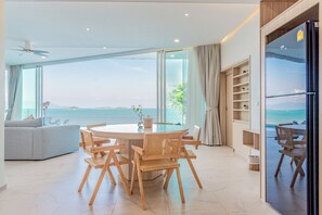Un amplio salón con una mesa redonda y sillas, un sofá, y vista al mar.
