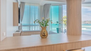 A modern room with a wooden desk, a decorative vase with flowers, and a view of the sea through large windows. - Replay Pool Villa  (Koh Samui)