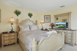 A bedroom with a large bed, two nightstands, a dresser, a television, and decorative wall art. - Spacious 6-bedroom house with AC and WiFi. 12 mins to Disney's Animal Kingdom (Kissimmee)