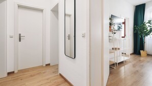 A hallway with white walls, wooden flooring, a large mirror, and a plant. - Homely Apartments Neu! Wlan Küche Altstadt-sbahn-dd, Elbufer Radweg (Meißen)