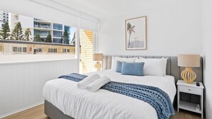 A modern hotel room with a large bed, a view of the city, and a balcony. - Beachfront Escape Broadbeach - 2BD, Pool, Sleeps 7 (Gold Coast)