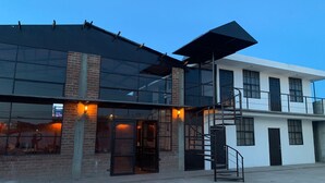 A modern building with a glass facade, a brick section, and a metal staircase. - Finca del Rincón (Guadalupe)