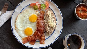 A breakfast plate with eggs, bacon, and toast, accompanied by a glass of orange juice, a bowl of salsa, and a cup of coffee on a wooden table. - Finca del Rincón (Guadalupe)