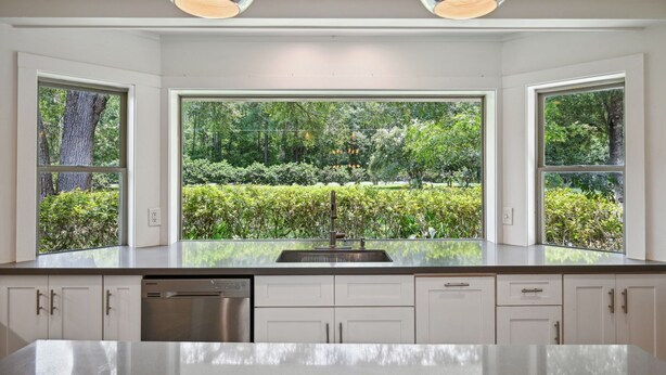 A modern kitchen with a large window, stainless steel appliances, and a clean, white cabinetry design. - "Whispering Oaks"  Enjoy this 4-bedroom home with HUGE backyard (Covington)