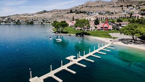 A coastal hotel with a marina, a red building, and a hilly backdrop. - Lake Chelan Shores: Sandy Beach Delight # 1-5; Chelan, WA. Beautiful 2-bdr condo (Chelan)