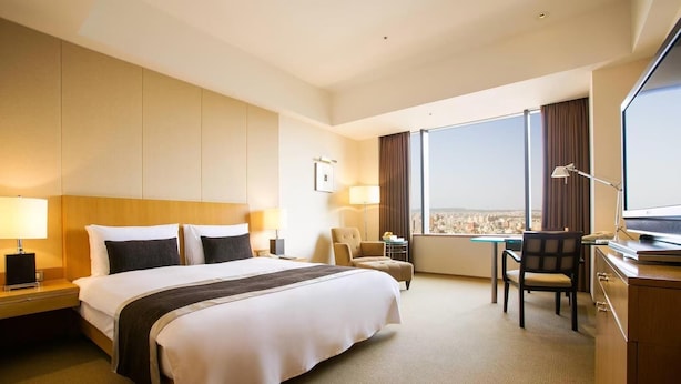 A hotel room with a large bed, a desk, a chair, and a view of the city. - Pingxiang Mubian Inn Friendship Branch (Chongzuo)