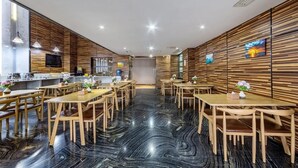 A modern restaurant with wooden panel walls, black marble flooring, and multiple dining tables and chairs. - Pingxiang Mubian Inn Friendship Branch (Chongzuo)