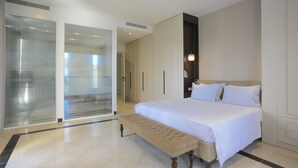 A modern hotel room with a large bed, a bench, a walk-in closet, and a glass door leading to a balcony. - L'Hôtel Particulier La Marsa (La Marsa)