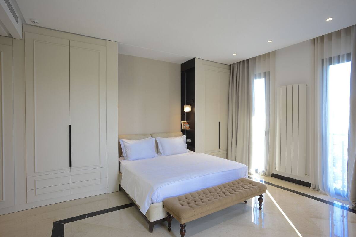 Ein geräumiges Schlafzimmer mit einem großen Bett, einer Bank und einem Kleiderschrank.