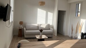 Ein modernes Wohnzimmer mit einer Couch, einem Couchtisch und einem an der Wand befestigten Fernseher.