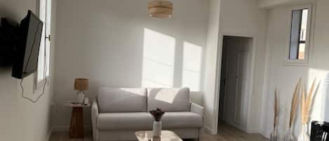 Una sala de estar moderna con un sofá, una mesa de centro y un televisor montado en la pared.