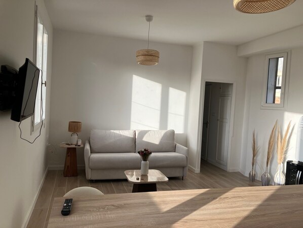 A modern living room with a sofa, a coffee table, and a TV mounted on the wall.