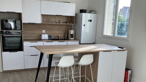 Eine moderne Küche mit weißen Schränken, einer Holz Arbeitsplatte, einem eingebauten Backofen, einer Kaffeemaschine und einem Fenster, das für natürliches Licht sorgt.