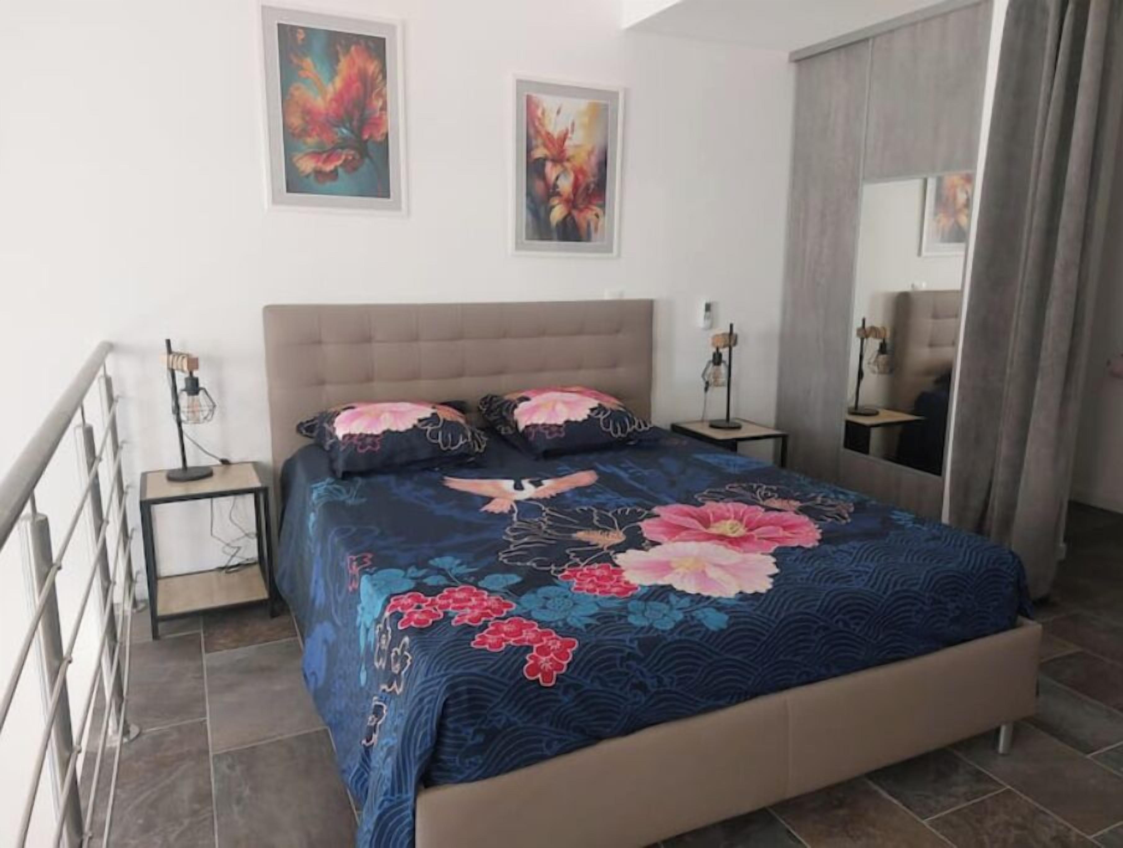 A bedroom with a large bed, two nightstands, a mirror, and artwork on the wall.