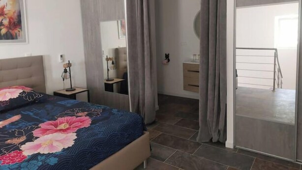 Ein Schlafzimmer mit Bett, Nachttisch, Schminktisch, Spiegel und einer Schiebetür, die auf einen Balkon führt.