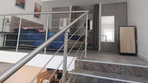 Eine moderne Wohnung mit Treppe, einem Bett, einem Kleiderschrank und einem Kühlschrank.
