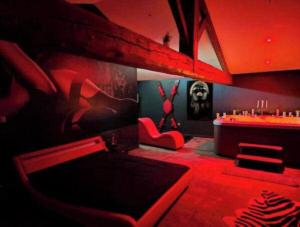 Relax in a stylish space with a large bed, a red armchair, and a zebra-patterned rug.