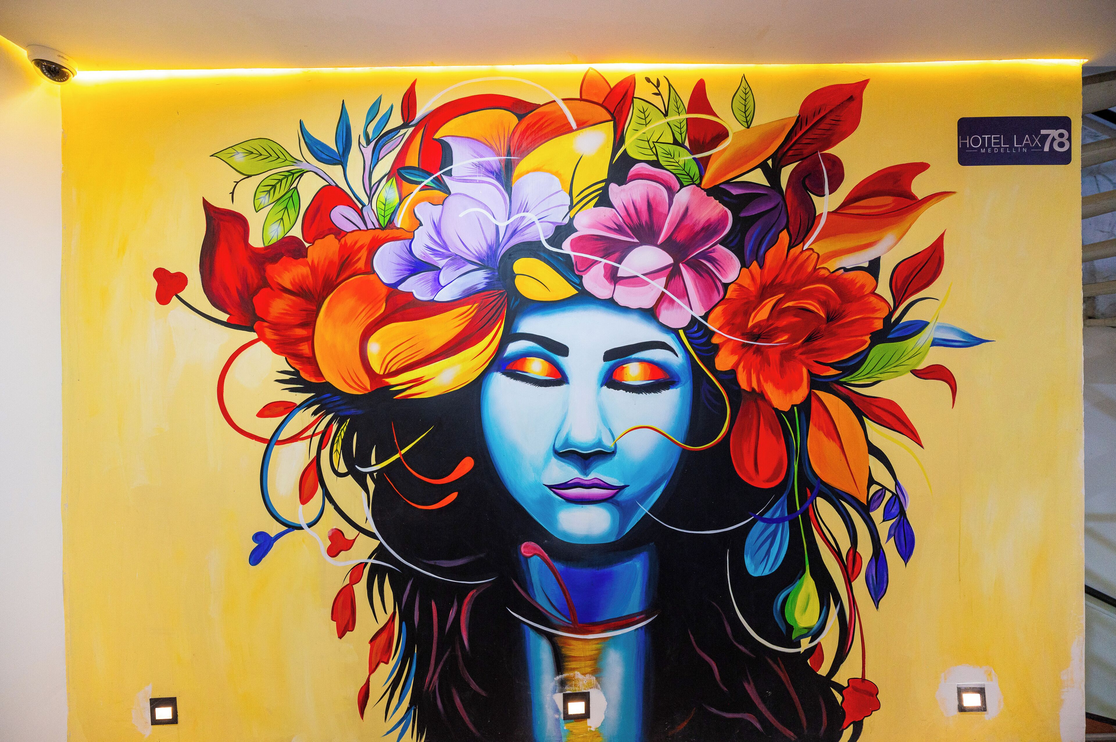 A vibrant mural with floral and abstract designs on a yellow wall.