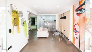 A modern interior with a white sofa, a glass partition, and a large mural. - HOTEL LAX  (Medellín)