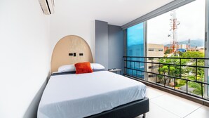 A modern hotel room with a large bed, a view of the city through a balcony, and a unique wall decoration. - HOTEL LAX  (Medellín)