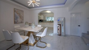 Un comedor moderno con una mesa de mármol, sillas blancas y una lámpara de techo original.