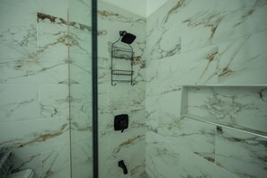 A bathroom with marble walls, a glass shower enclosure, and a black towel rack. - Tuscany Sun Villa at Legacy Townhouse (Thompson Town)