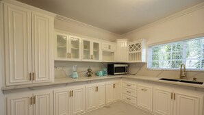 Una cocina con armarios blancos, microondas y fregadero.