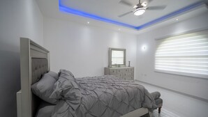 Un dormitorio con cama, cómoda y ventilador de techo.