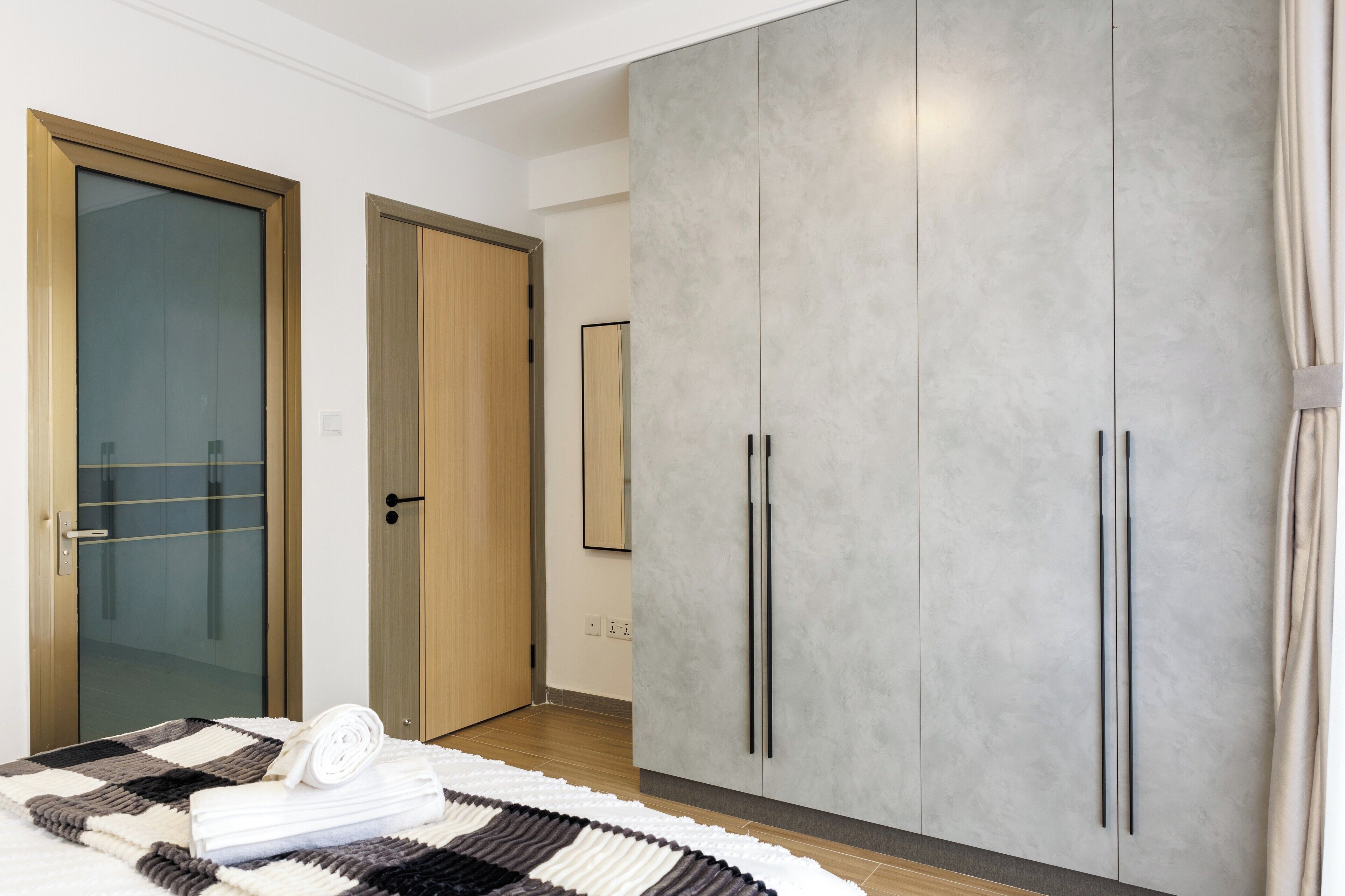 A bedroom with a bed, a large wardrobe, and a mirror.